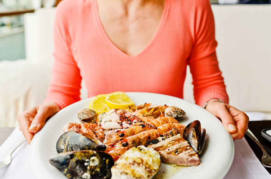 Imagen de persona con plato de mariscos