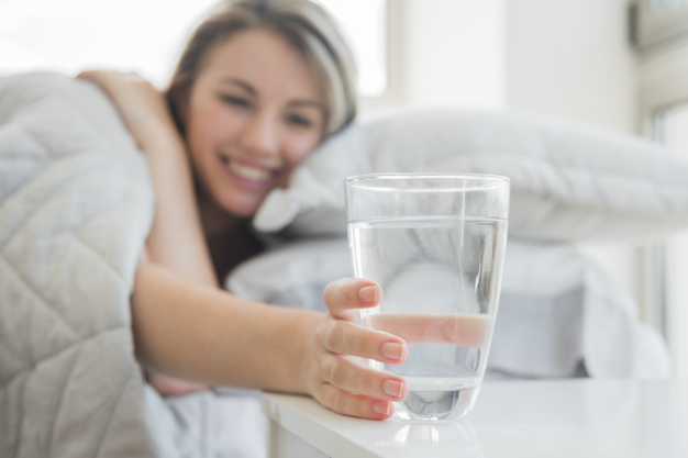 chica feliz pudo descansar con un vaso de agua debajo de la cama